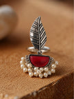 Oxidised silver leaf ring with red half-moon stone and pearl drops displayed upright on burlap surface