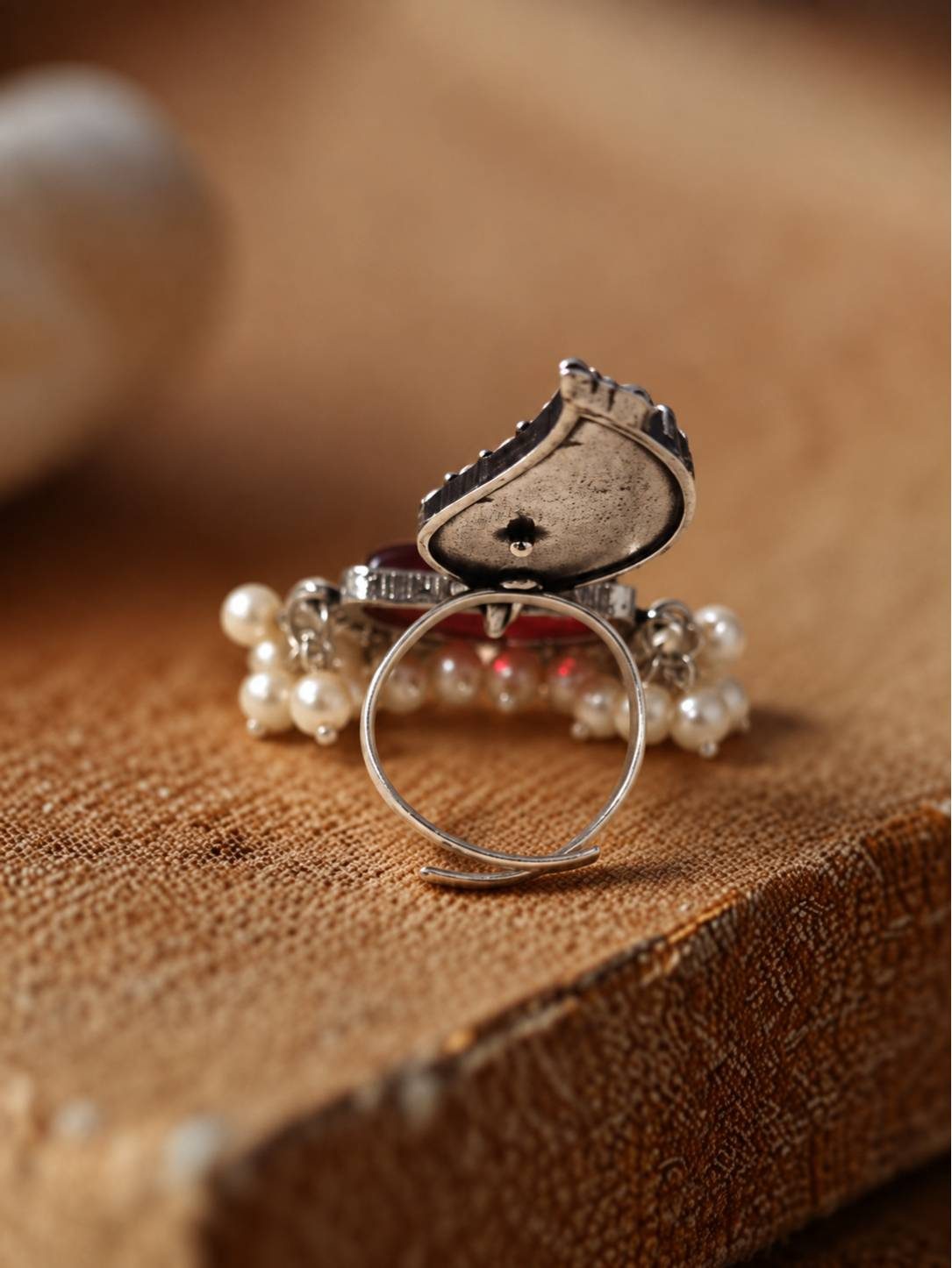 Back view of oxidised silver leaf ring showing open adjustable band and reverse of red stone setting