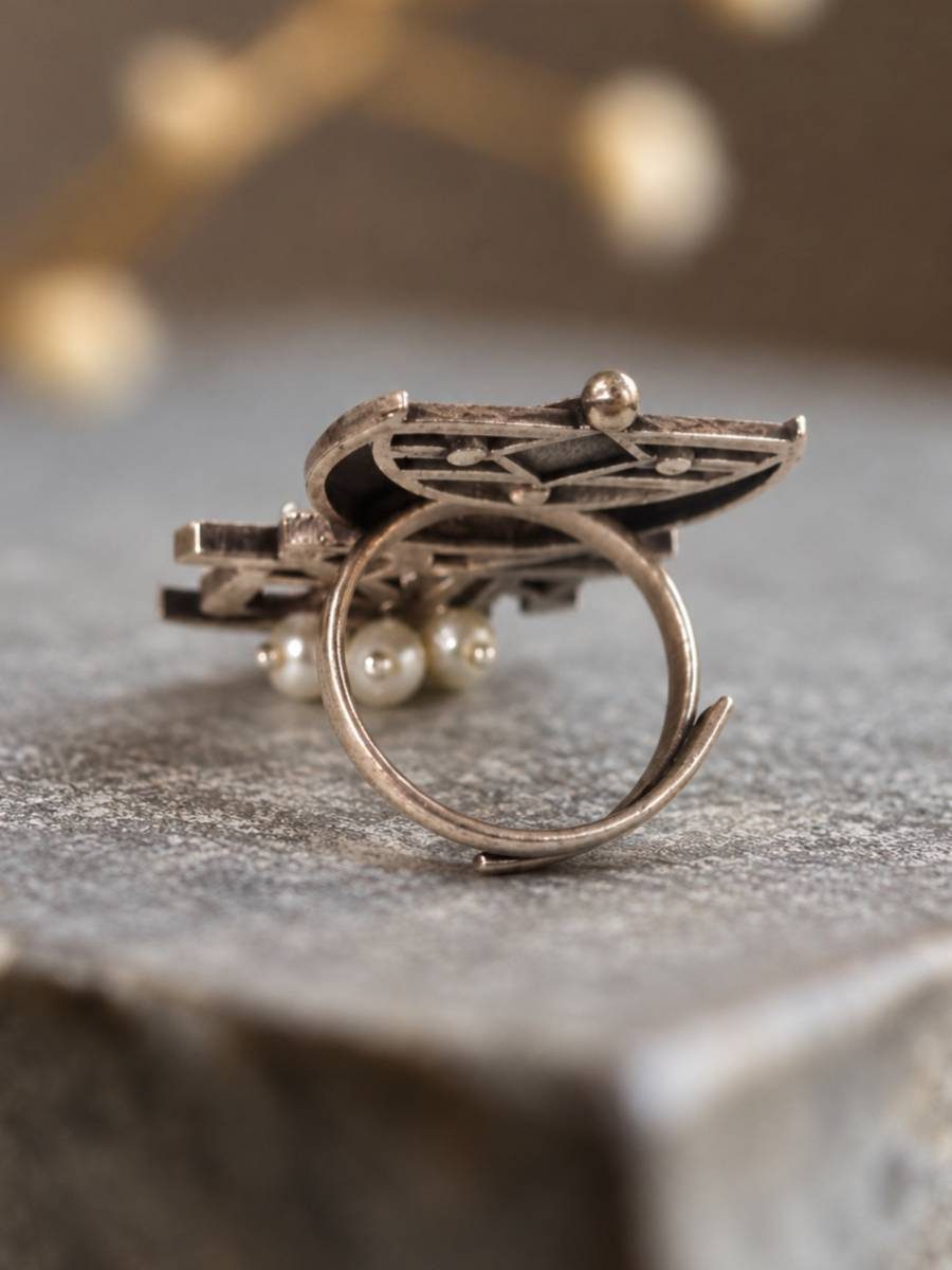 Side view of oxidised silver Mohi ring showing open adjustable band and intricate filigree back detail with small pearl drops