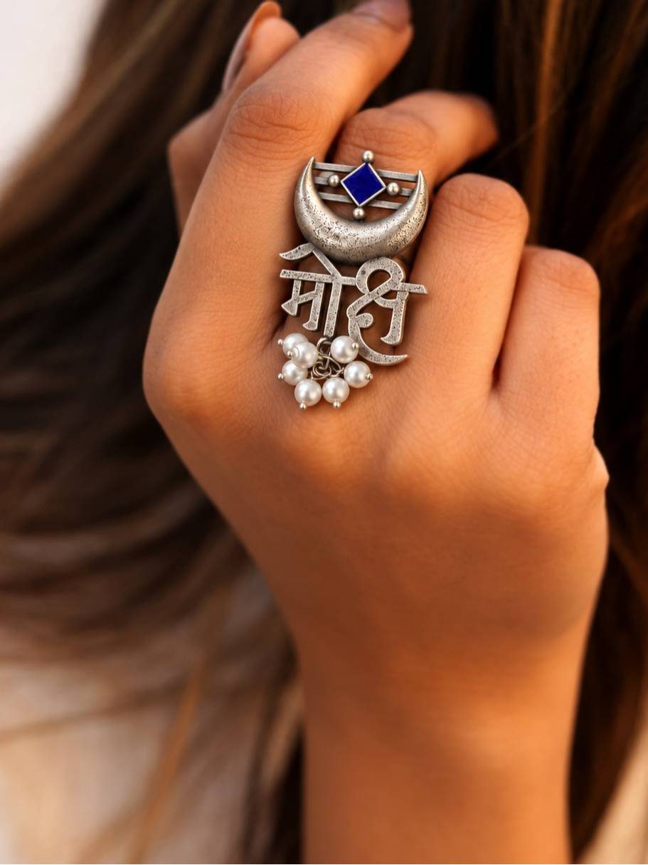 Mohi oxidised silver statement ring worn on middle finger of a woman's hand against dark hair background