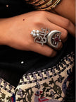 Moksh script ring worn on hand against black embroidered fabric showing pearl drops and crescent moon from front angle