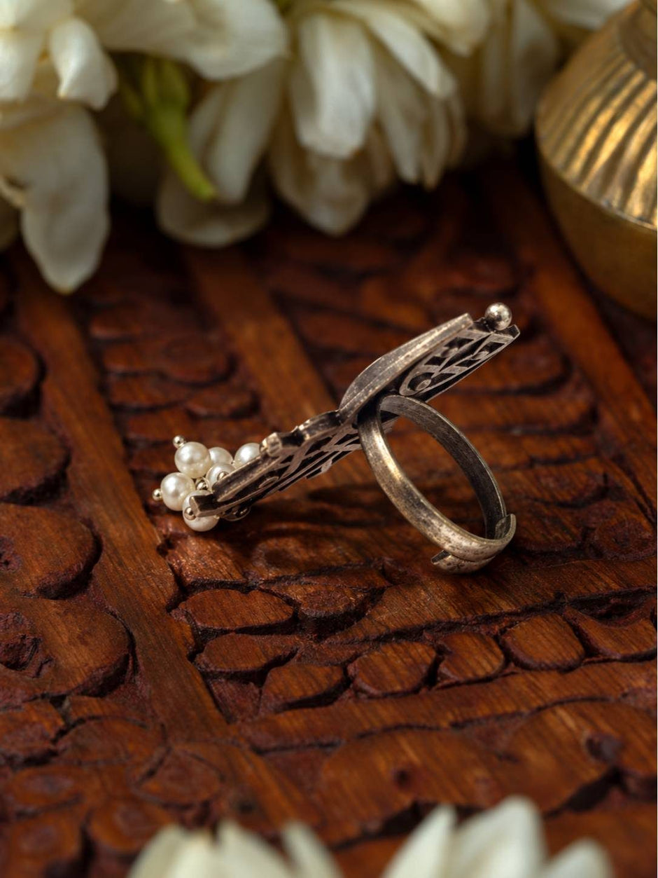 Side profile of oxidised silver Mohi ring showing adjustable open band and pearl cluster against carved wooden background