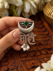 Close-up of Mohi script ring held between fingers showing green stone bezel crescent moon and hanging pearl drops