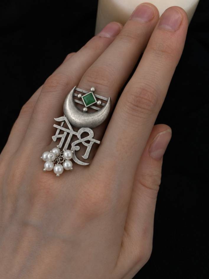 Oxidised silver Mohi Devanagari ring worn on middle finger showing full design with green stone and pearl drops