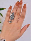 Oxidised silver leaf ring worn on index finger with terracotta french-tip nails