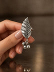 Hand holding oxidised silver leaf ring close up showing veined leaf detail and dangling ghungroos