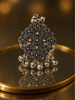 Front view of oxidised silver floral ring with ghungroo bells on a gold mirror tray