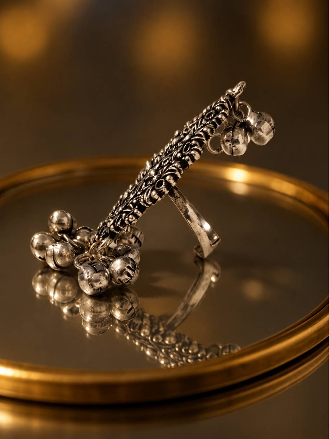 Side profile of oxidised silver ring with braided top band and cluster of ghungroo bells