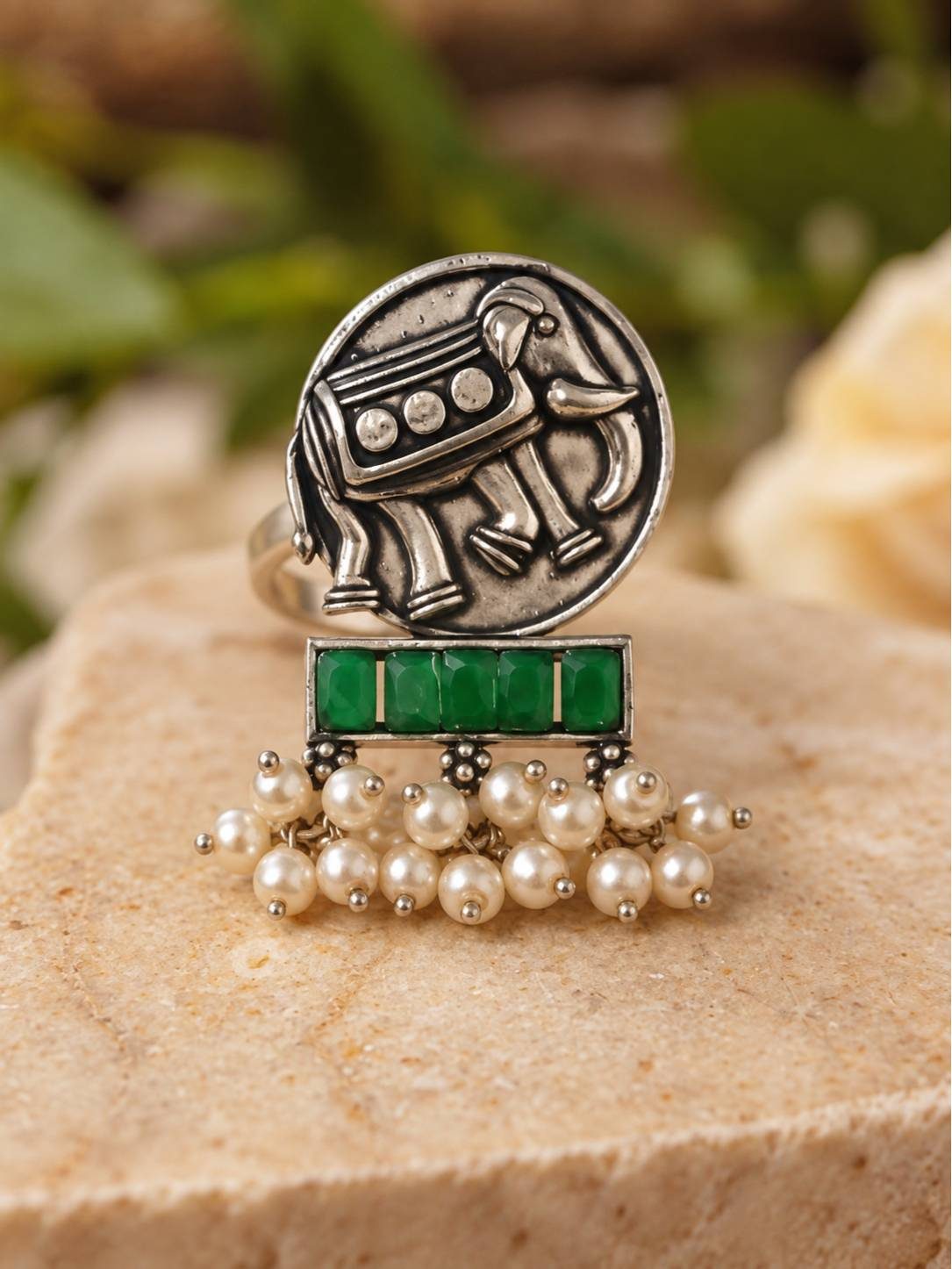 Front view of oxidised silver elephant coin ring with green baguette stones and white pearl drop dangles