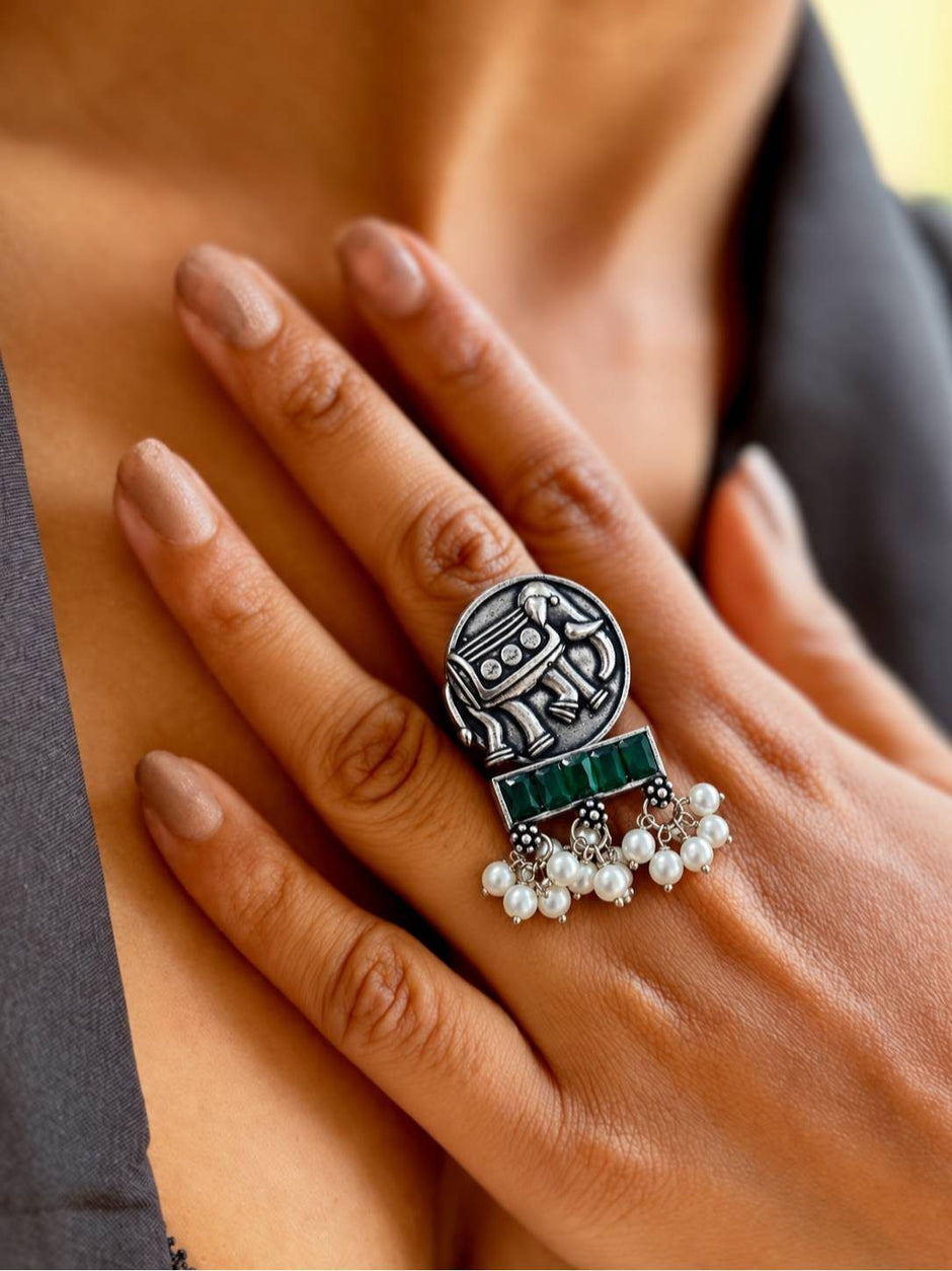 Oxidised silver elephant ring with green stones and pearl drops worn on woman's middle finger
