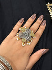 Oxidised silver dual-tone floral cocktail ring worn on a woman's finger against a black fabric background