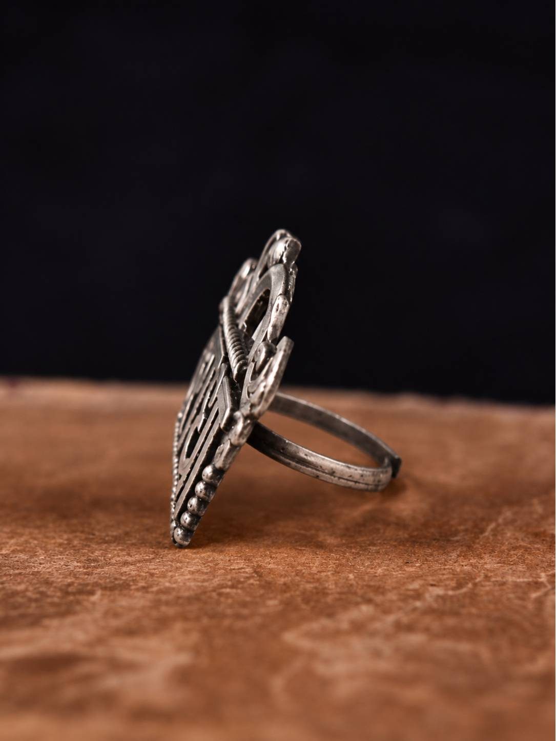 Side profile of oxidised silver Radha ring showing depth of carved Devanagari lettering and slim band