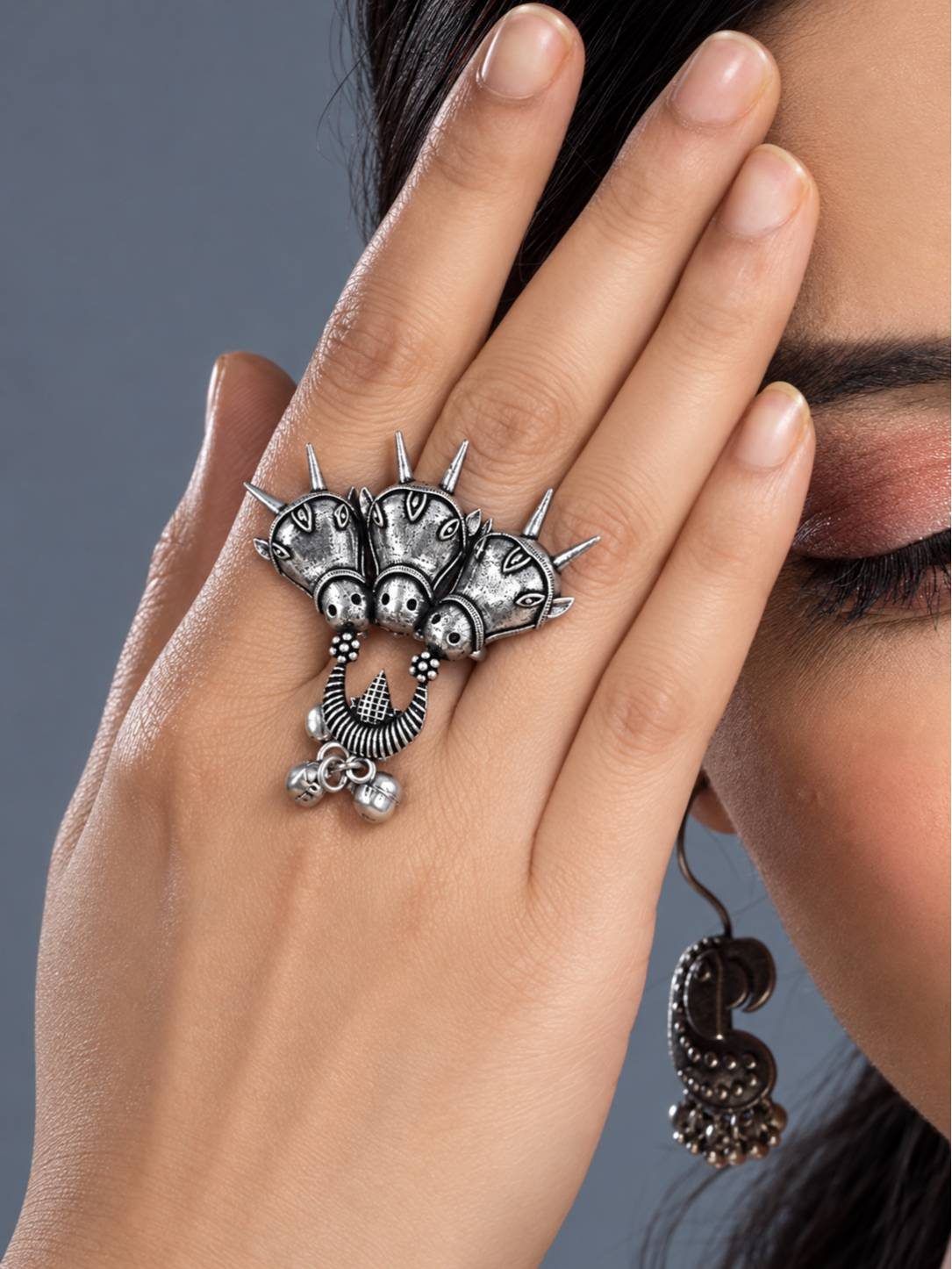 Oxidised silver triple horse head ring worn on a woman's index finger alongside a jhumka earring