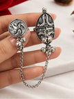 Close-up of oxidised silver dual finger ring held in hand showing floral oval top and circular bird motif ring