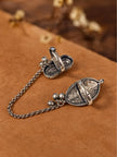 Back view of oxidised silver dual finger rings opened to reveal hollow locket cavities, resting on brown suede
