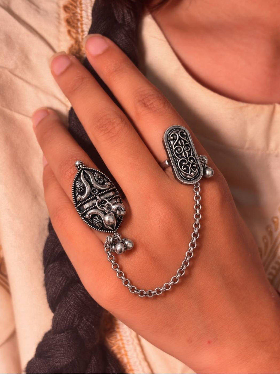 Oxidised silver dual finger chain ring worn on index and middle finger against a draped fabric background