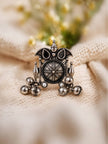 Front view of oxidised silver statement ring with sun wheel disc, black stones, and dangling ghungroo bells on cream fabric