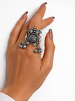 Oxidised silver ghungroo cocktail ring worn on middle finger of a woman's hand against a white background