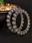 Two oxidised silver coin bangles propped upright showing detailed portrait coin engravings and antique finish close up