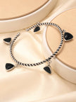 Two oxidised silver triangle charm cuff bracelets side by side on a cream satin surface with a round platform
