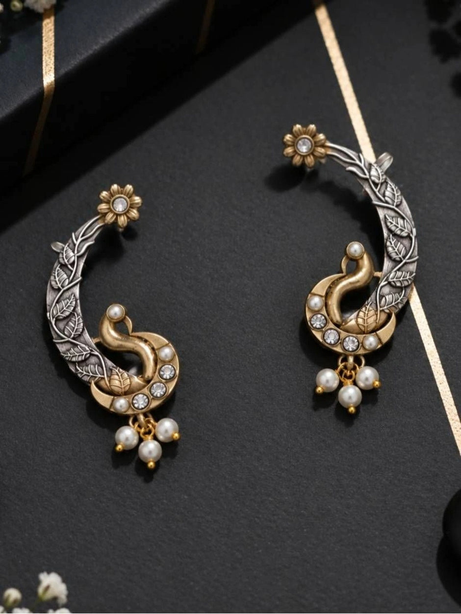 Close-up of peacock ear cuff pair on black surface highlighting crystal and pearl embellishments