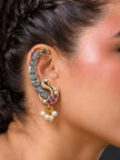 Peacock ear cuff earring worn on a woman's ear showing full profile and gold daisy stud