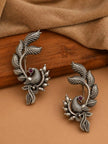 Two oxidised silver bird ear cuff earrings displayed on a wooden surface with suede backdrop