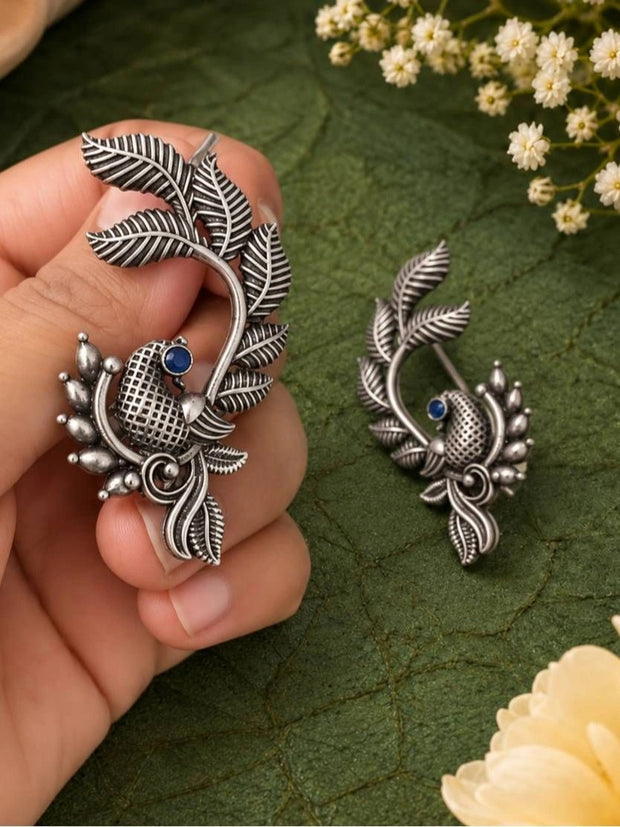 Hand holding large oxidised silver peacock ear cuff showing intricate leaf and feather detail