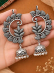Pair of oxidised silver leaf chandbali jhumka earrings with pearl drops resting on a woman's open palm