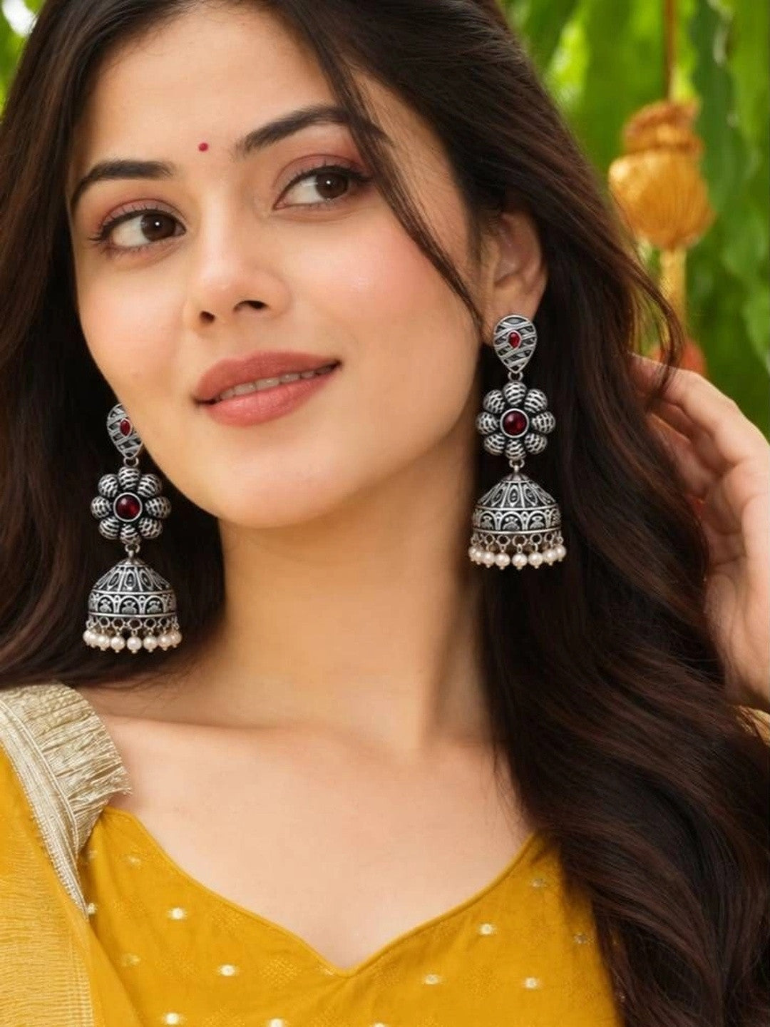 Woman wearing oxidised silver floral jhumka earrings with red stones and pearl drops with yellow kurta