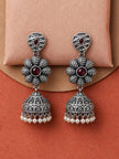 Front view of oxidised silver jhumka earrings with floral centre and dangling pearl drops on display stand