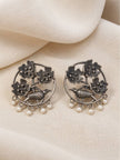 Front view of oxidised silver floral bird earrings with pearl drops laid flat on cream fabric