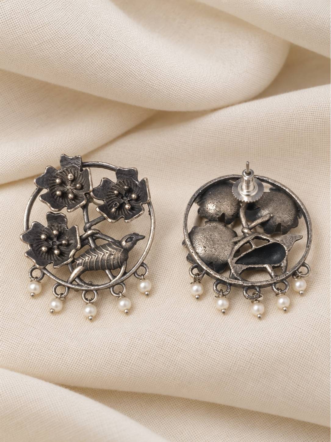 Front and back view of oxidised silver chandbali earrings showing push-back stud closure on cream fabric