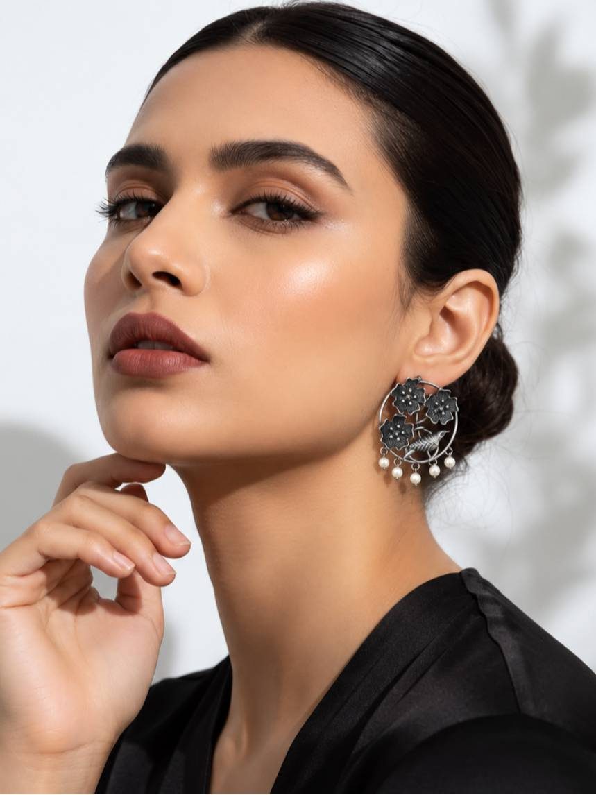 Woman wearing oxidised silver bird and floral chandbali earrings with pearl drops with a black outfit
