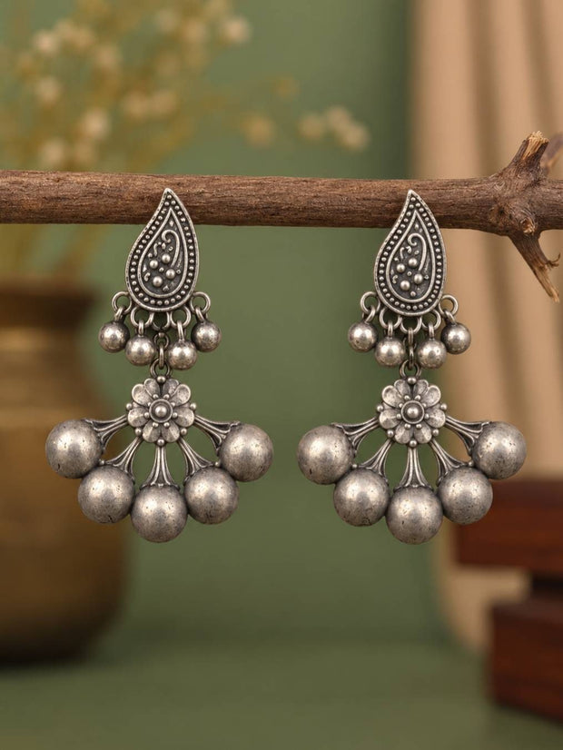 Pair of oxidised silver chandbali earrings with paisley stud and five ghungroo balls hanging from a wooden branch