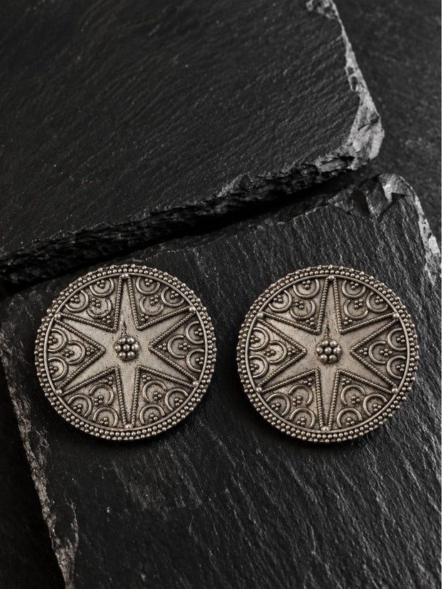 Pair of circular oxidised silver mandala stud earrings displayed on dark slate stone