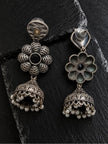 Front and back view of oxidised silver floral jhumka earrings on dark slate surface