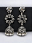 Pair of oxidised silver floral jhumka earrings with engraved dome and pearl beads on dark board