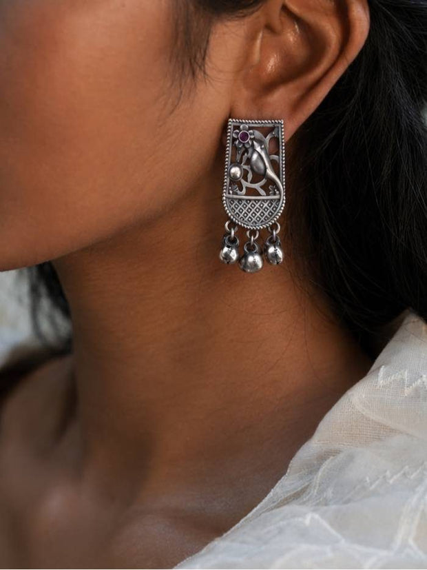 Oxidised silver bird motif ghungroo stud earring worn on a woman's ear shown in close-up side profile