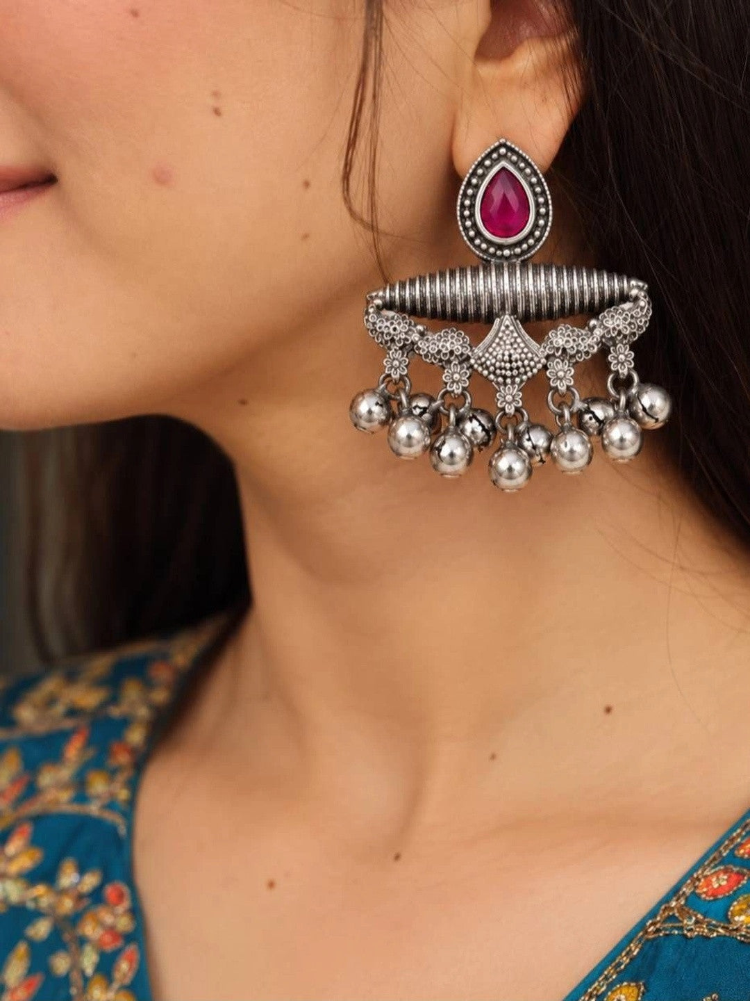 Woman wearing oxidised silver chandbali earring with pink teardrop stone and silver ghungroo ball drops, styled with a teal floral kurta