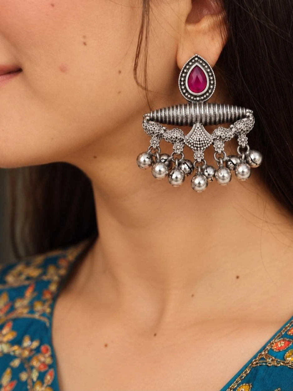 Woman wearing oxidised silver chandbali earring with pink teardrop stone and silver ghungroo ball drops, styled with a teal floral kurta