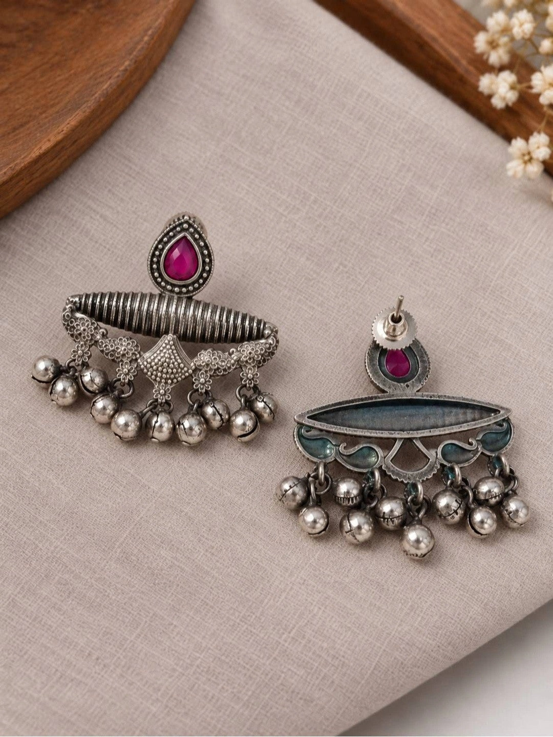 Front and back view of oxidised silver chandbali earring pair laid flat on grey linen fabric, showing screw-back closure