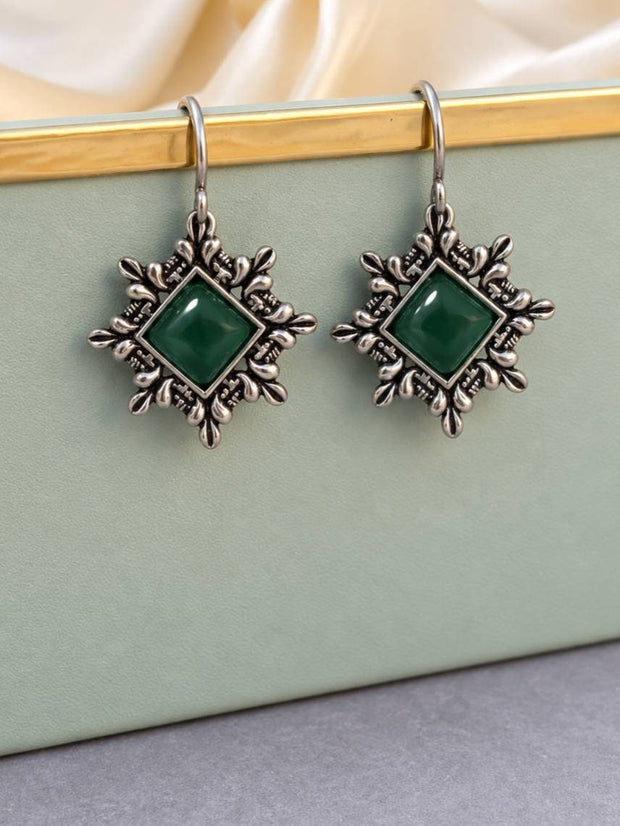 Pair of oxidised silver dangle earrings with green square cabochon stone displayed on a mint jewellery box