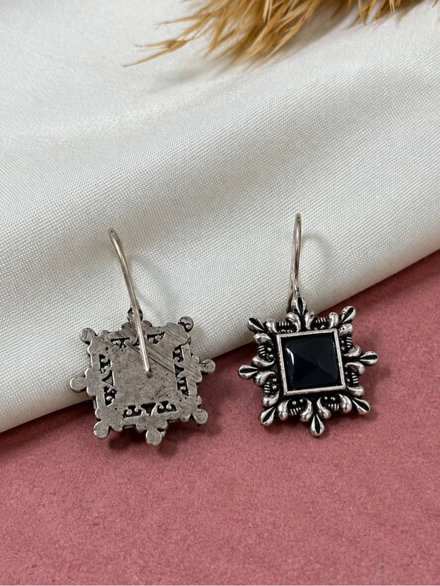 Front and back view of oxidised silver square earrings showing detailed reverse metalwork on pink background