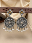 Pair of oxidised silver chandbali earrings displayed on wooden rack showing lotus motif and pearl drops