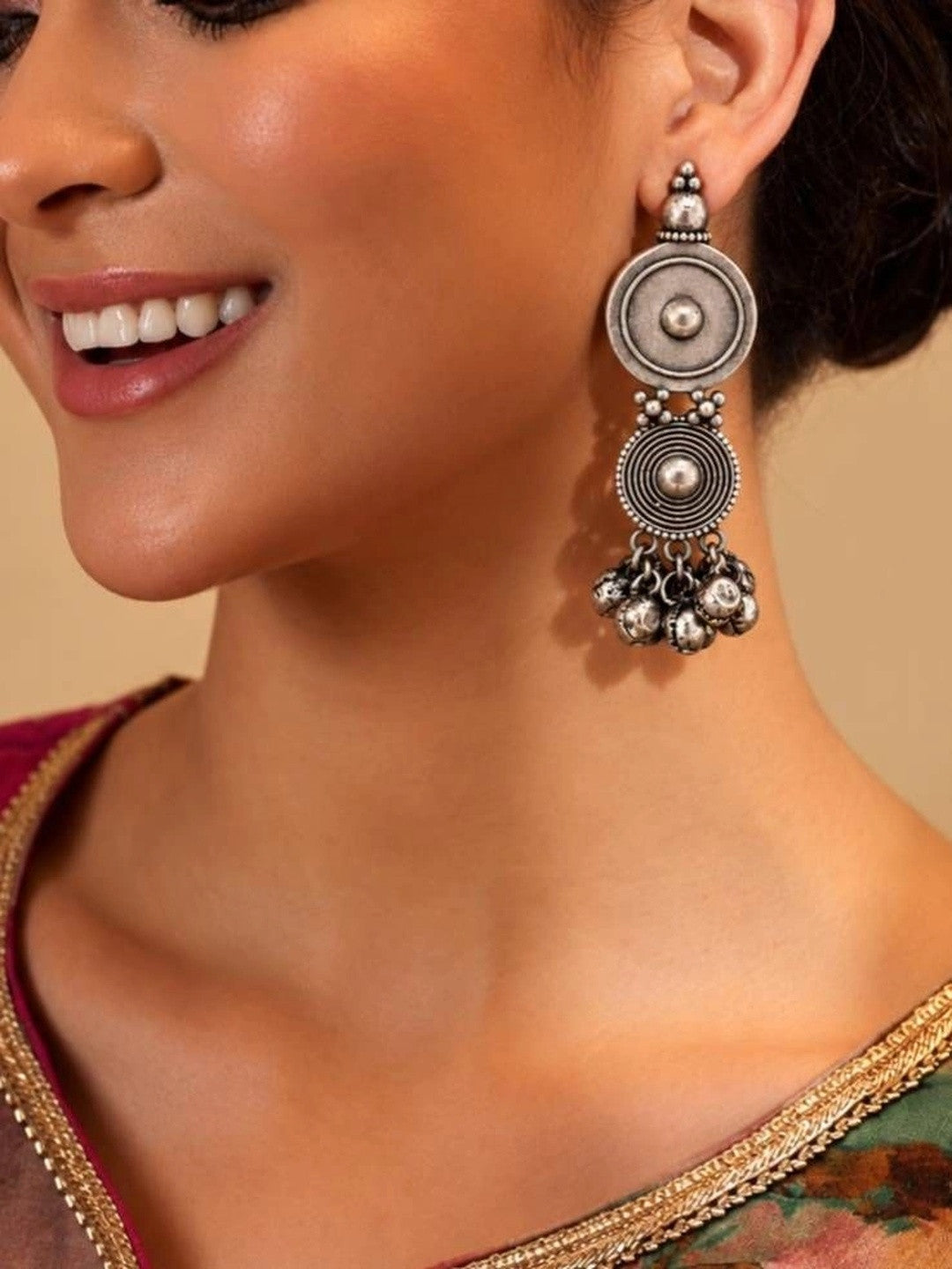 Woman wearing oxidised silver dual disc ghungroo drop earring with a silk saree