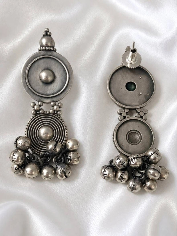 Front and back view of oxidised silver disc drop earrings with ghungroo bells on white satin