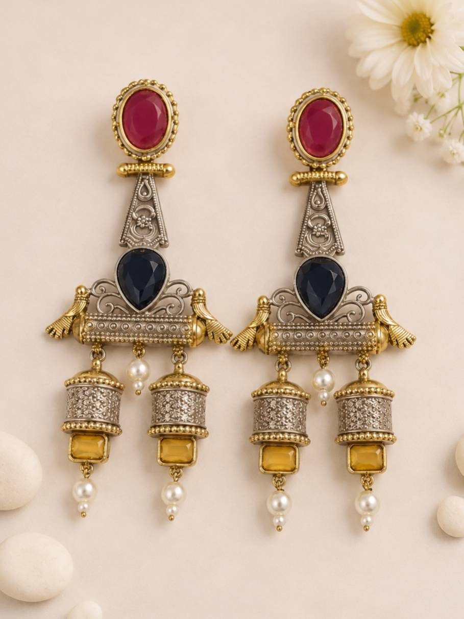 Front flat-lay of dual-tone oxidised jhumka earrings on cream background with daisies showing full earring detail
