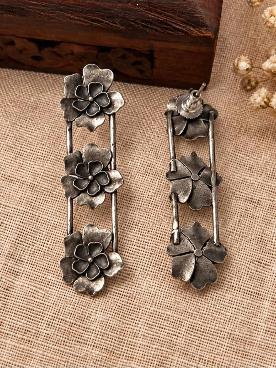 Front and back view of oxidised silver floral drop earrings showing push-back stud closure on burlap
