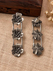 Front and back view of oxidised silver floral drop earrings showing push-back stud closure on burlap